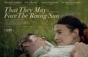 Poster for That They May Face the Rising Sun, Barry Ward lying in a grass field looking down at Anna Bederke resting her head on his chest, and looking up at him.