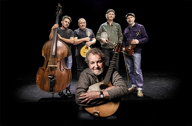 Studio shot of Quilty (four Swedish men holding string instruments) standing behind a crouching Andy Irvine, who is hugging a bouzouki to his chest.