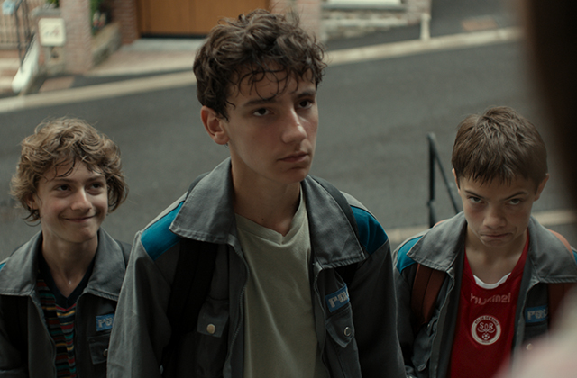 A still from The Fantastic Three depicting three scruffy-looking boys in their early teens, dressed in identical wide-collar jackets, looking up with cheeky expressions.