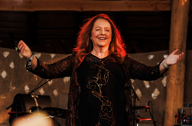 Mary Coughlan, on stage, arms outstretched, looking joyous