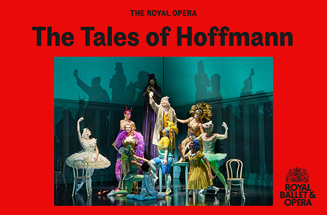 Still from the stage production of the Royal Opera's The Tales of Hoffman. A man stands on a chair, centre stage, raising a glass in a toast. He is surrounded by multiple actors, all dressed in brightly coloured party clothes.