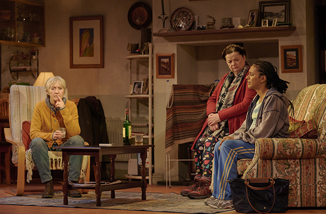 Jane Brennan, Helen Norton and Fanta Barrie sitting, looking concerned in a living room set.