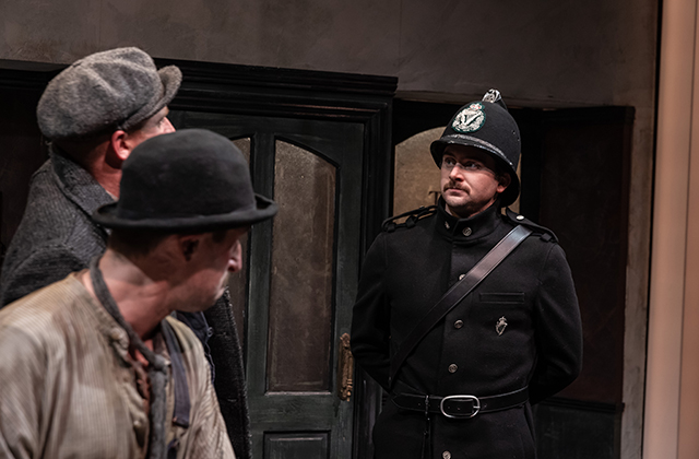 A British-style police officer confronting two men.