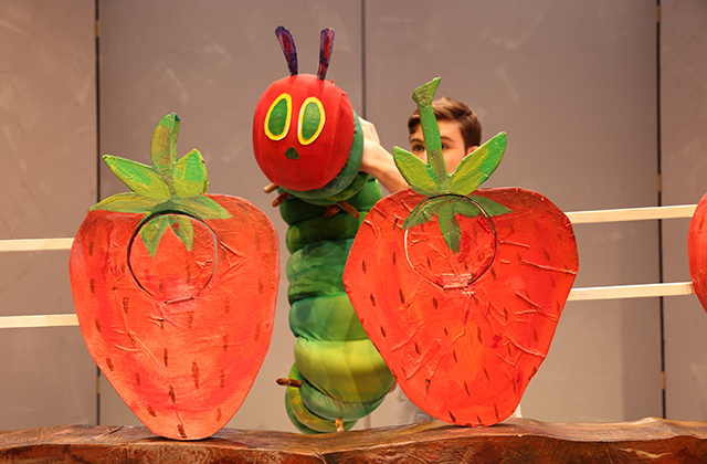 The Very Hungry Caterpillar puppet eyeing up two huge, juicy strawberries.