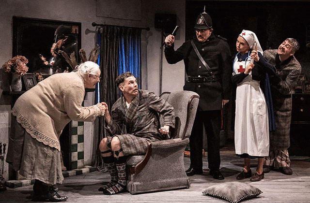 Left to right: Marie Mullen, Marty Rea, Rory Nolan, Venetia Bowe and Liam Heslin are together on stage. Marty is sitting in a dressing gown in an arm chair while the others crowd around him.